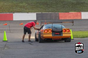 A man is working on a sports car on a track.