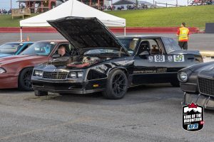 A group of cars with their hoods open in a parking lot.