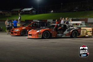 A group of cars parked in a parking lot at night.