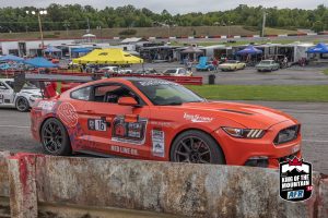 A ford mustang is driving down a race track.