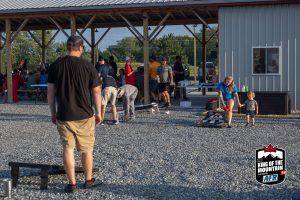 A group of people playing frisbee in a gravel lot.