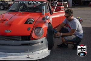 A man is working on a red sports car.