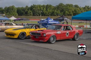 Two cars parked next to each other at a race track.