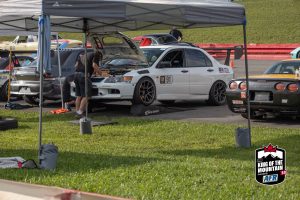 A group of people working on cars under a tent.