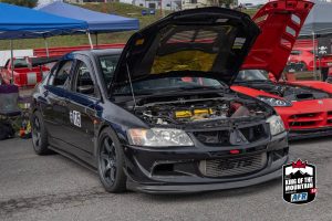 A black car with its hood open at a car show.