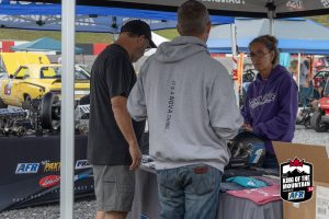 A group of people standing around a tent at an outdoor event.