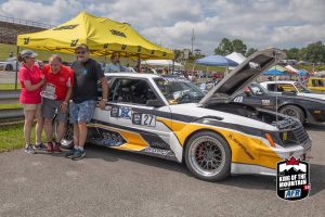 A group of people standing next to a race car.