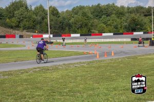A group of people riding bikes on a track with cones.