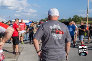A man in a red t - shirt is standing in a crowd.