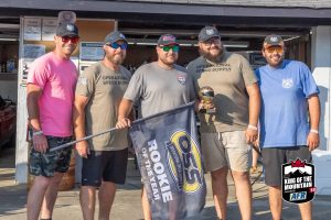 A group of men posing for a picture in front of a garage.