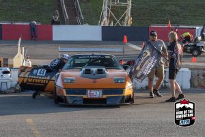 A group of people standing next to a race car.