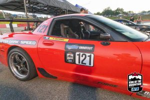 A red corvette race car is parked in a parking lot.