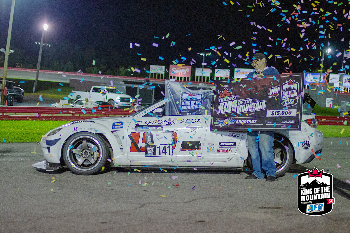A man standing next to a race car with confetti.