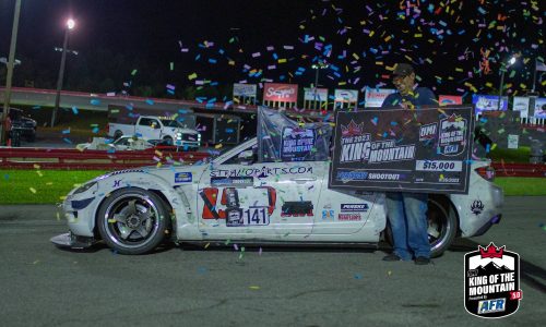 A man standing next to a race car with confetti.