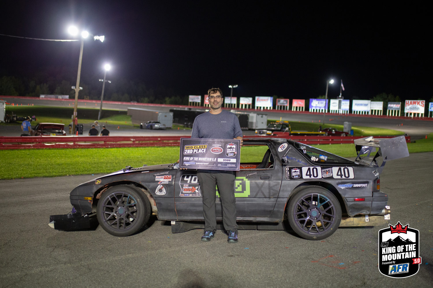 A man standing next to a race car at night.